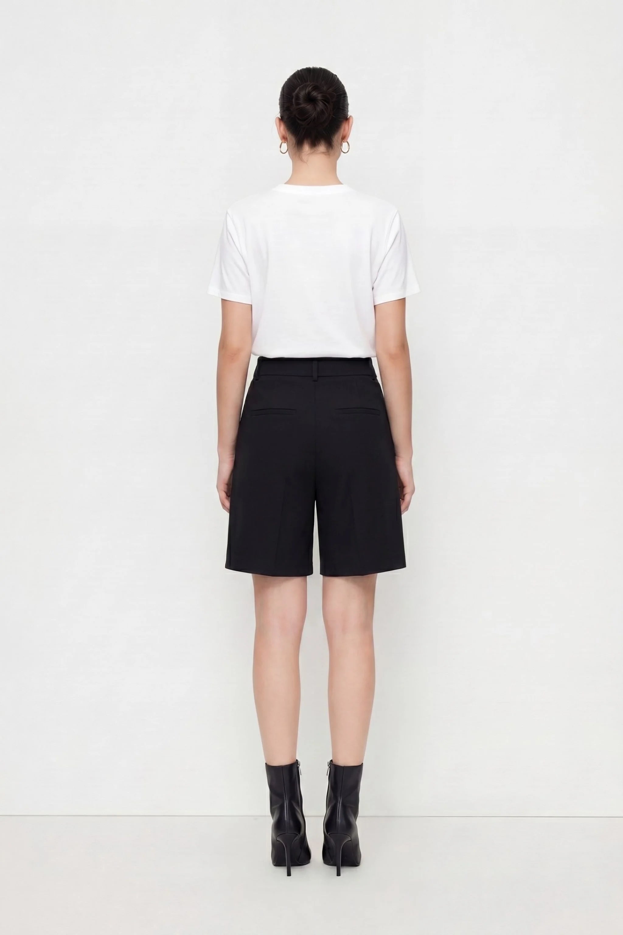 Person wearing a white t-shirt and black shorts on a white background
