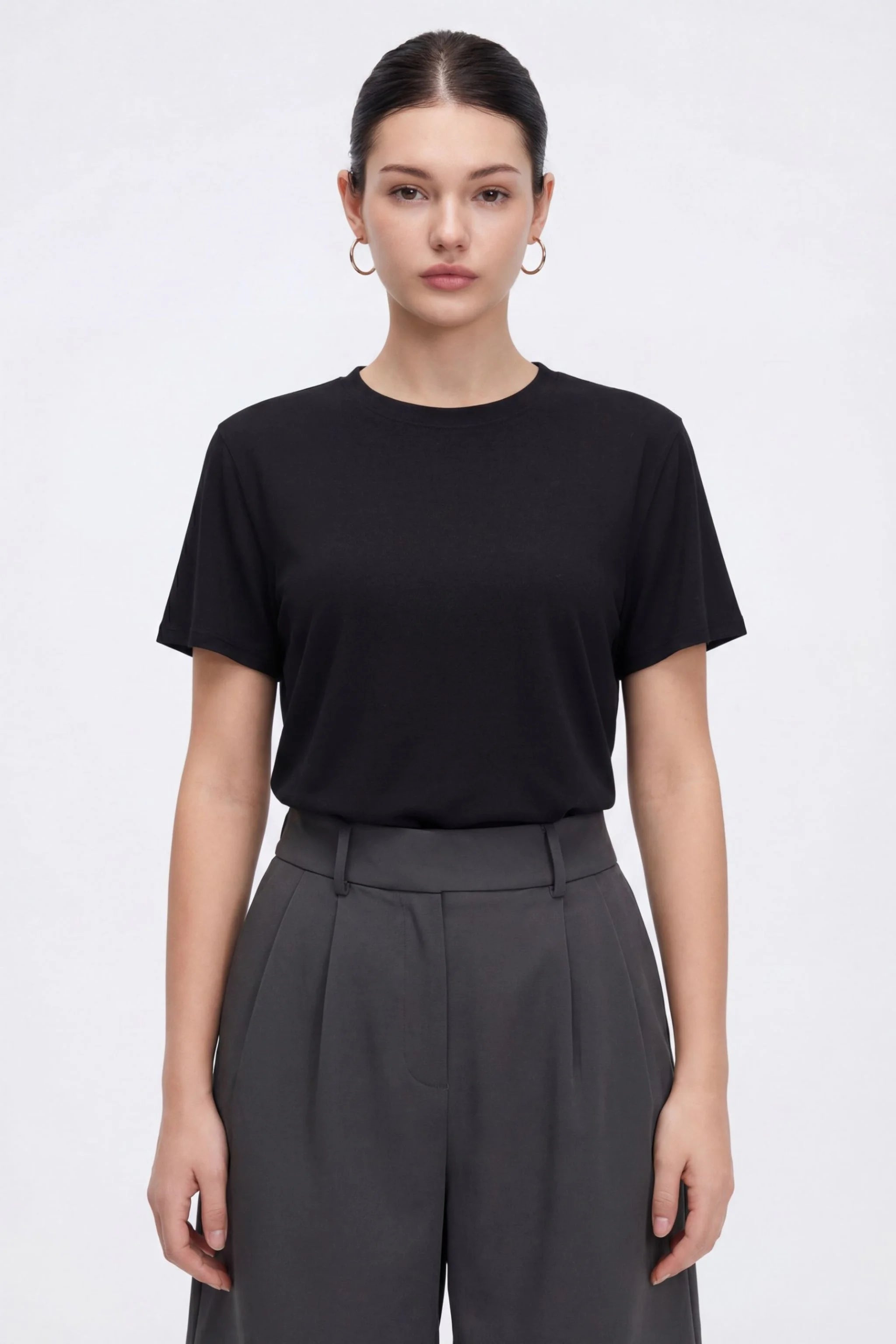 Person wearing a black t-shirt and gray pants on a white background