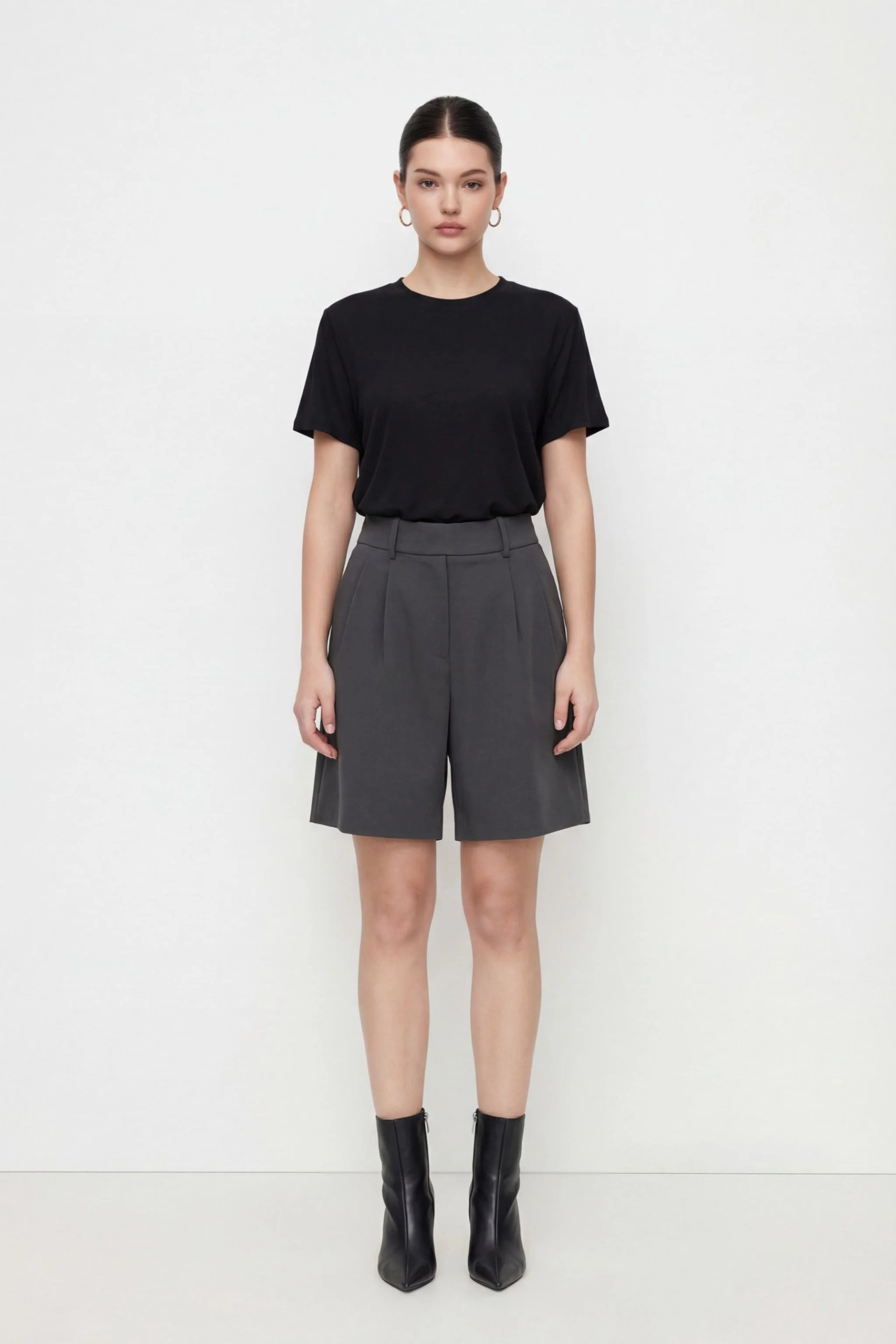 Person wearing a black t-shirt and gray shorts on a white background